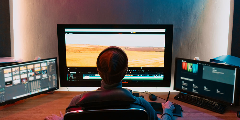 Montażysta podczas postprodukcji filmu, pracujący nad korekcją barwną na wielu monitorach, co jest ważnym etapem wpływającym na koszt filmu reklamowego.