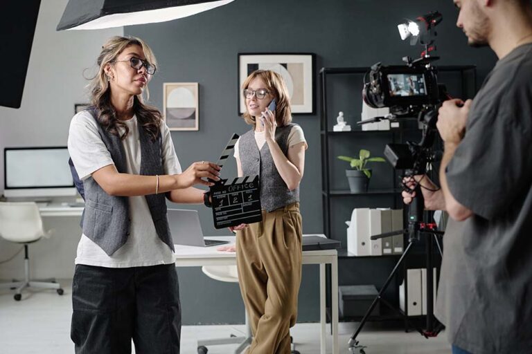 Kobieta na planie filmowym trzymająca klaps, co symbolizuje etap produkcji w procesie tworzenia filmu biznesowego.